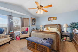 Carpeted bedroom with vaulted ceiling and ceiling fan