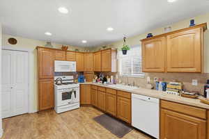 Kitchen with white appliances, light countertops, recessed lighting, tasteful backsplash, and brown cabinets