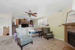 Living area featuring a glass covered fireplace, a ceiling fan, stairs, and recessed lighting