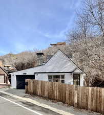 View of property exterior featuring a fenced front yard, a chimney, and a garage