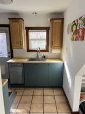 Kitchen with healthy amount of natural light, light tile patterned floors, decorative backsplash, and dishwasher