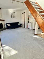 Living area featuring carpet, track lighting, and a brick fireplace