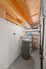 Unfinished below grade area featuring a water softener system and electric water heater