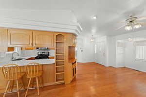 Kitchen with open shelves, light countertops, a breakfast bar area, stainless steel appliances, and ceiling fan