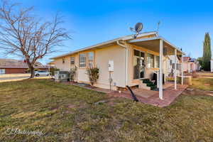 Rear view of house with a yard, stucco siding, a patio area, and entry steps