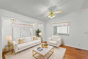Living area with lofted ceiling, ceiling fan, and wood finished floors