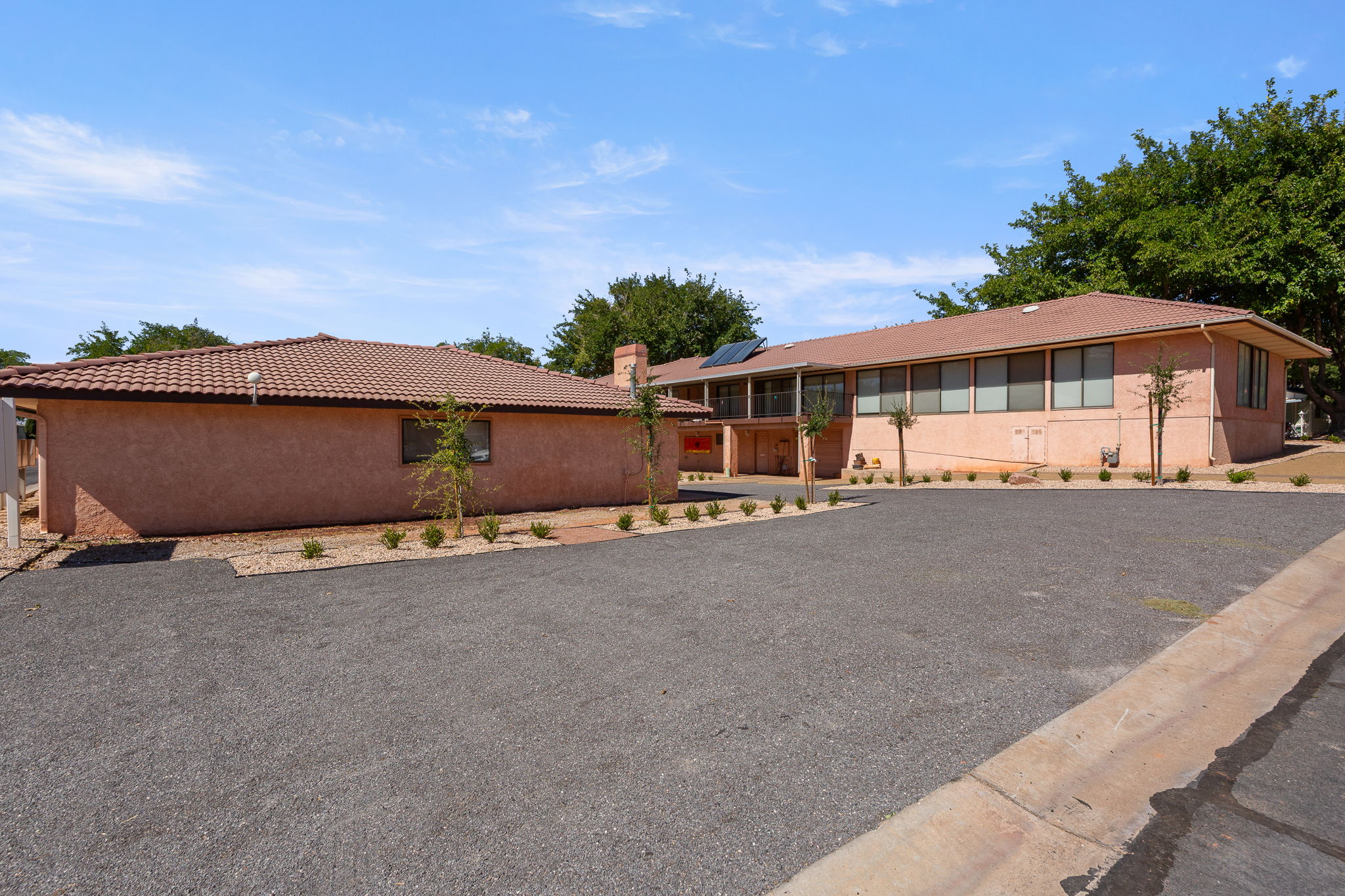 Ranch-style home featuring a tile roof, roof mounted solar panels, a chimney, and stucco siding
