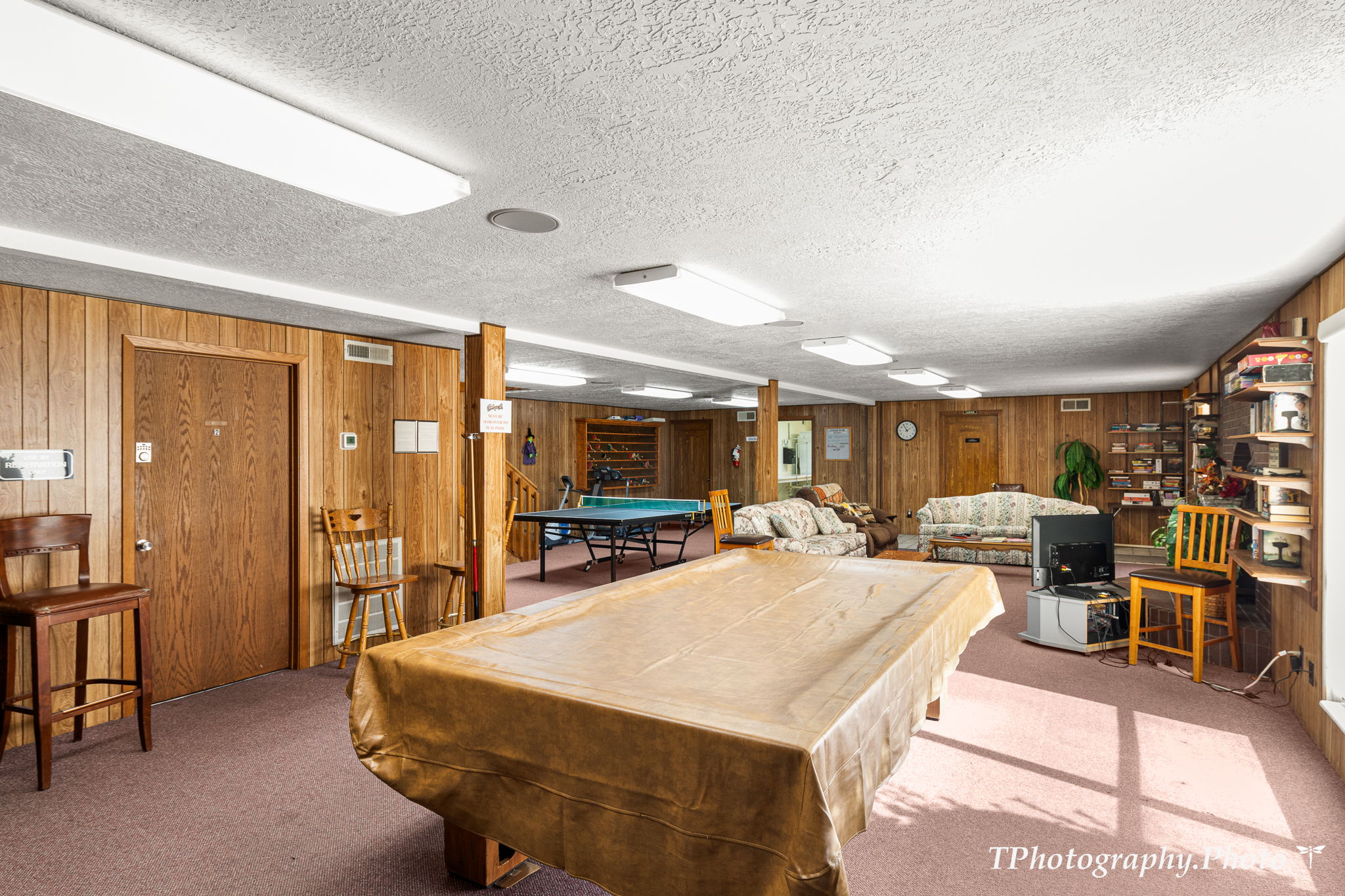 Game room with billiards, wood walls, a textured ceiling, and carpet