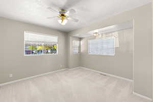 Spare room featuring light colored carpet, ceiling fan, and a textured ceiling