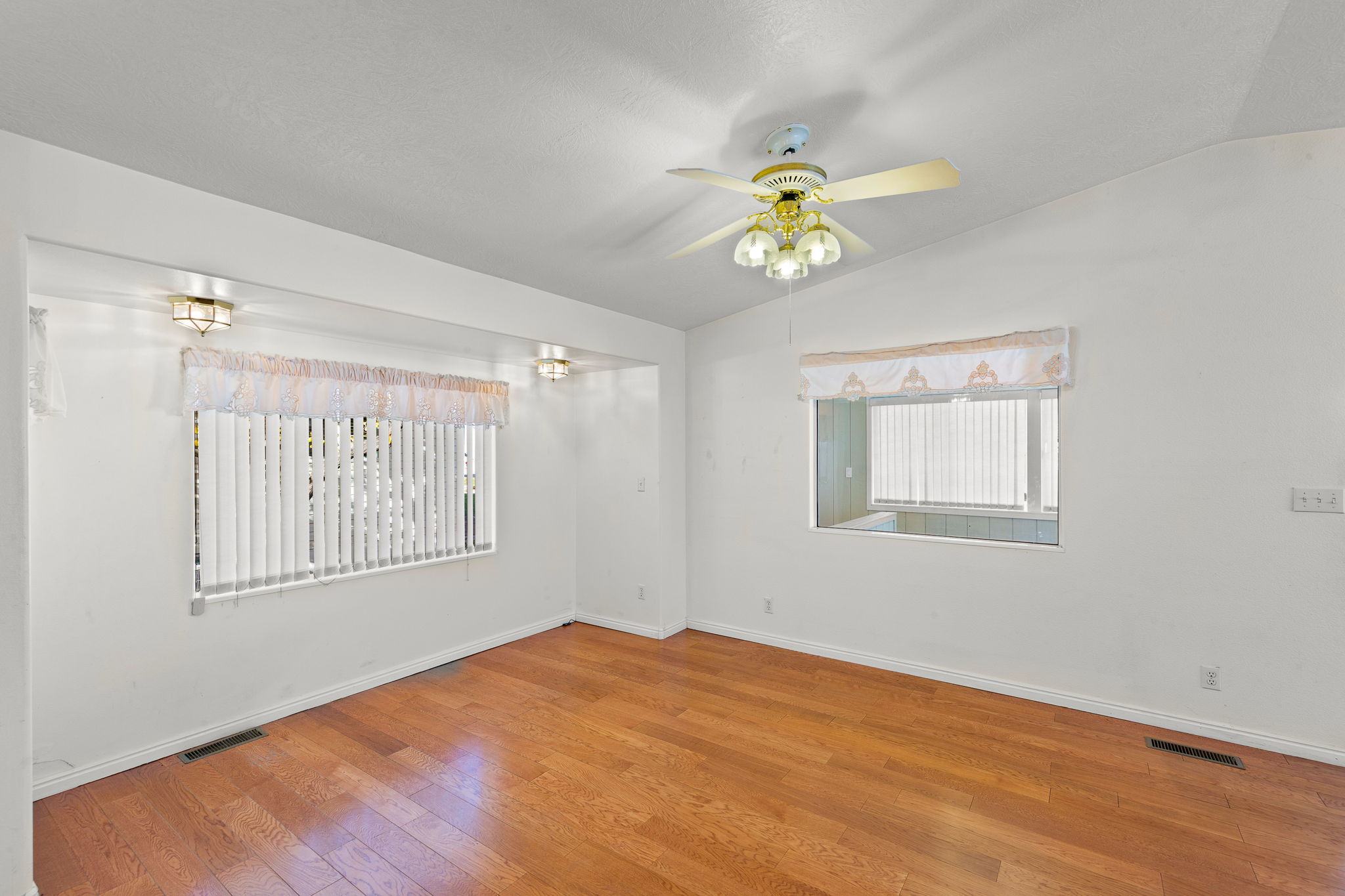Empty room with vaulted ceiling, wood-type flooring, and ceiling fan