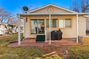 Rear view of property with a yard, stucco siding, and a patio area