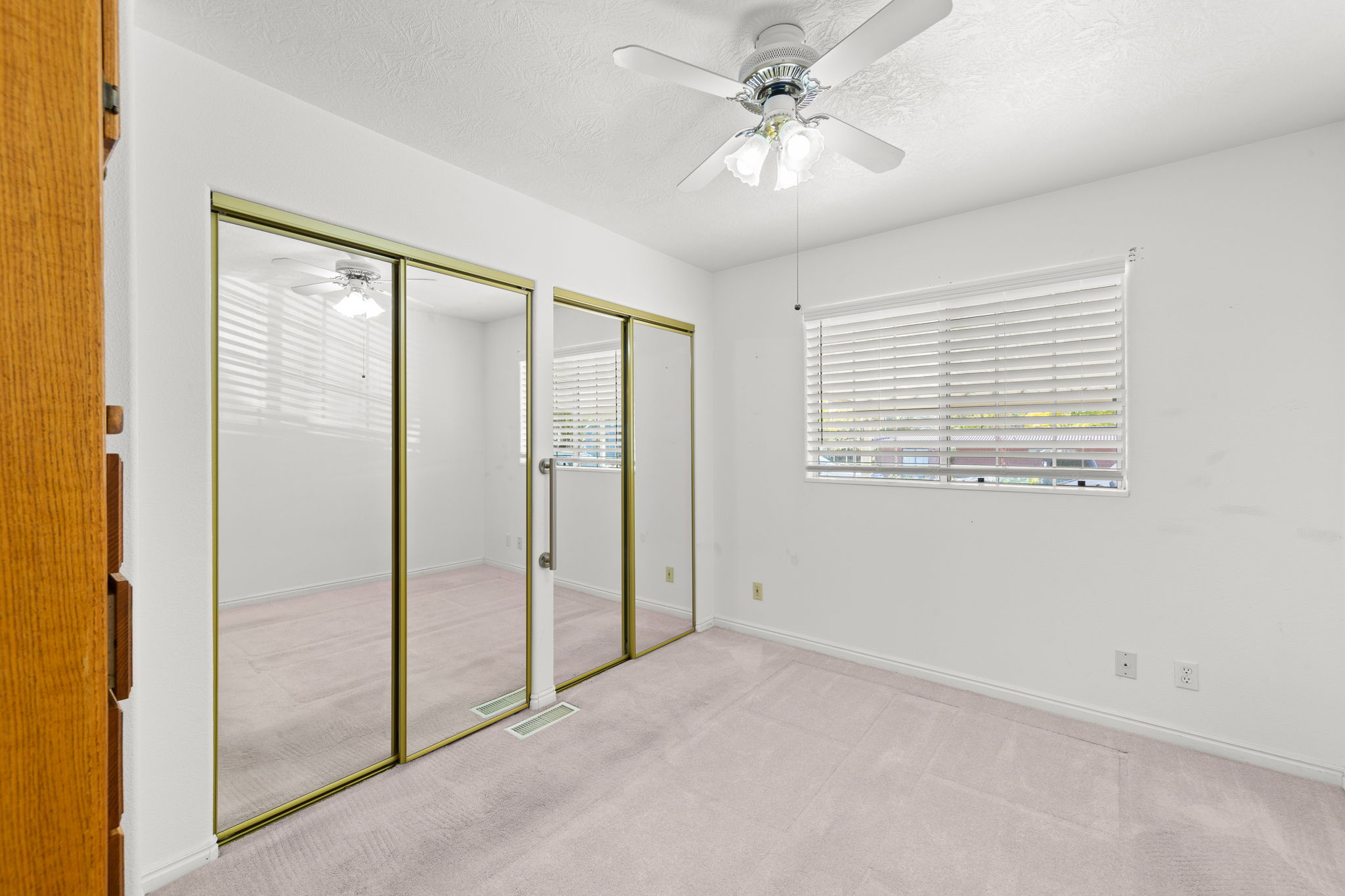 Unfurnished bedroom with two closets, carpet, a textured ceiling, and ceiling fan