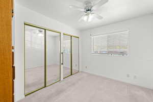 Unfurnished bedroom with two closets, carpet, a textured ceiling, and ceiling fan