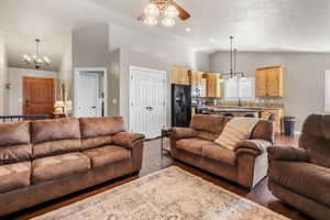Living room featuring vaulted ceiling, a ceiling fan, dark wood-type flooring