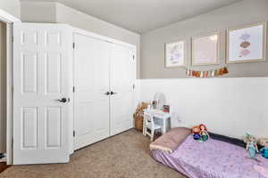 Carpeted bedroom with wainscoting and large  closet