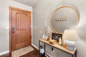 Foyer featuring dark wood finished floors and baseboards