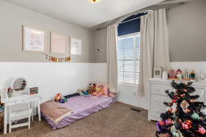 Carpeted bedroom with a wainscoted wall and large window with transom