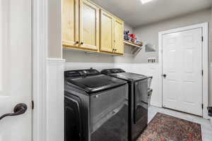Laundry room with a wainscoted wall, cabinet space, independent washer and dryer, and closet