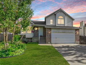 Split level home featuring a garage, driveway, brick siding, and roof with shingles