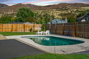 View of swimming pool featuring a mountain view, a fenced backyard, and a patio area