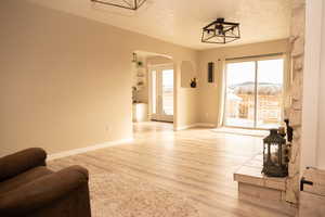 Living room with arched walkways, a textured ceiling, and light wood finished floors