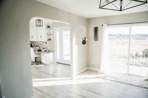 Entrance foyer with arched walkways, healthy amount of natural light, a textured wall, and light wood-style flooring