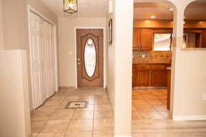 Foyer entrance featuring light tile patterned flooring and arched walkways