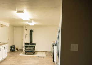 Below grade area featuring a wood stove, a textured ceiling, and light wood finished floors