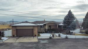 Ranch-style home with a fenced front yard, concrete driveway, brick siding, and a garage