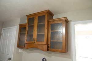 Detailed view of brown cabinets, glass insert cabinets, and a textured ceiling