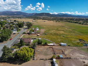 Aerial view of property and surrounding area featuring a mountainous background and rural landscape