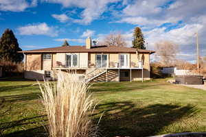 Rear view of property with stairway, a lawn, and a chimney