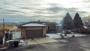 Single story home with a fenced front yard, brick siding, driveway, a garage, and a mountain view