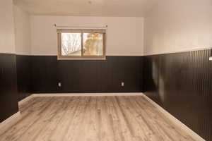 Spare room featuring a wainscoted wall and light wood-style floors