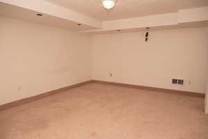 Spare room with a textured ceiling and light carpet