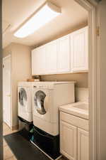 Laundry area featuring cabinet space, independent washer and dryer, and light tile patterned flooring