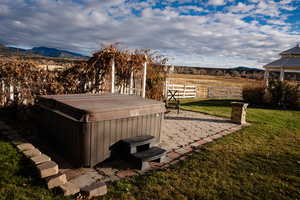 View of yard featuring a patio area, a hot tub, and a mountain view