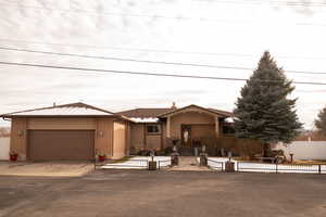Ranch-style home featuring a fenced front yard, a garage, driveway, and brick siding