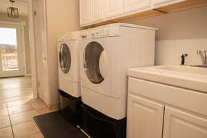 Laundry room featuring washing machine and clothes dryer, light tile patterned floors, and cabinet space