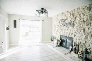 Unfurnished living room with wood finished floors, a textured ceiling, a glass covered fireplace, and arched walkways