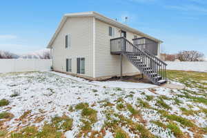 Snow covered property with a fenced backyard and stairway