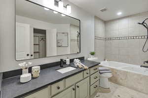 Bathroom with vanity, tiled shower / bath combo, and a walk in closet
