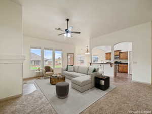 Living room featuring light colored carpet, a chandelier, ceiling fan, and arched walkways