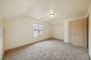 Additional living space with lofted ceiling and carpet floors