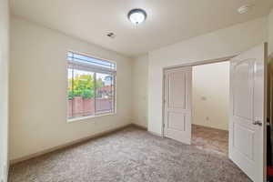 Unfurnished bedroom with light colored carpet and baseboards