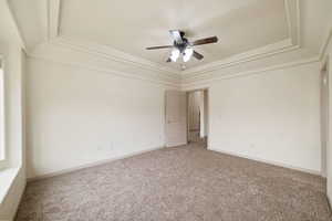 Carpeted empty room with a raised ceiling and ceiling fan