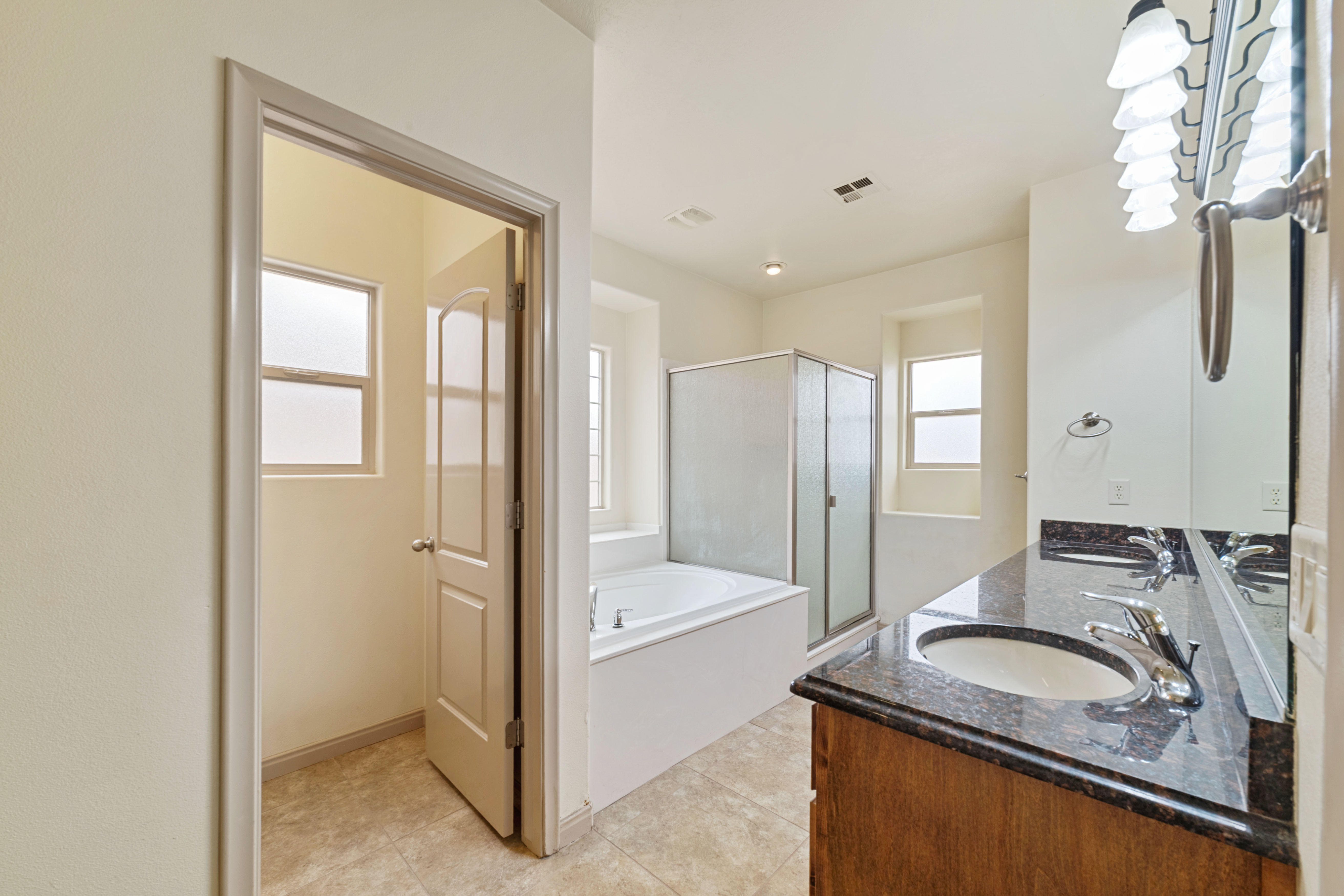 Full bathroom with a bath, a shower stall, double vanity, and light tile patterned floors