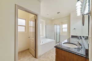 Full bathroom with a bath, a shower stall, double vanity, and light tile patterned floors