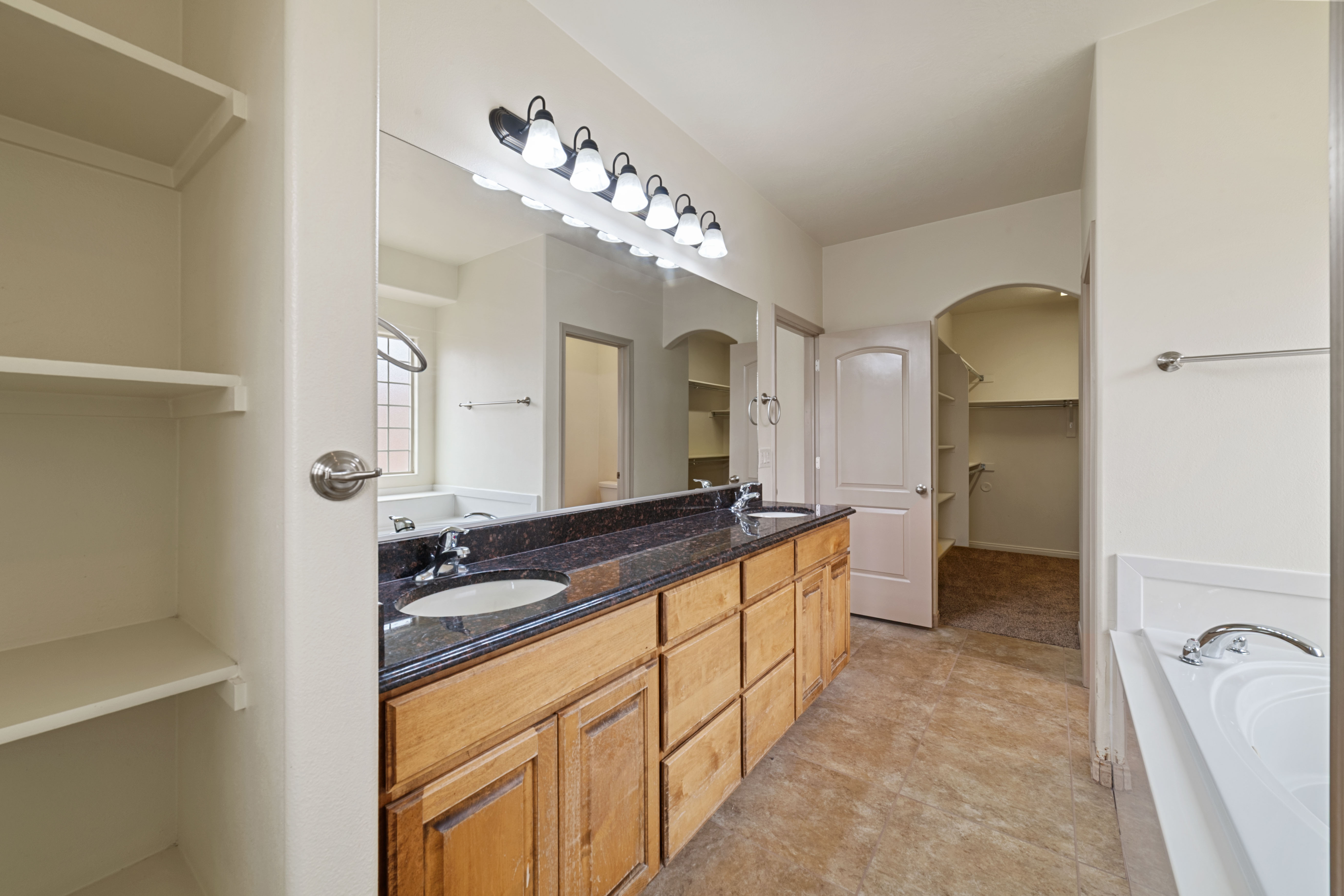 Bathroom with a bath, a spacious closet, and double vanity