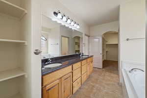 Bathroom with a bath, a spacious closet, and double vanity